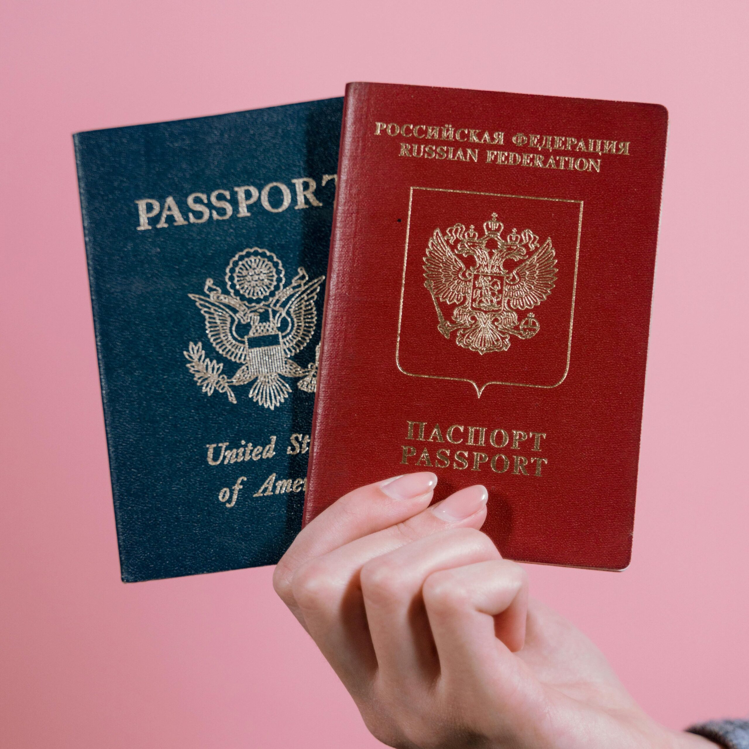 Es werden ein blauer und ein roter Reisepass in der Hand gehalten.