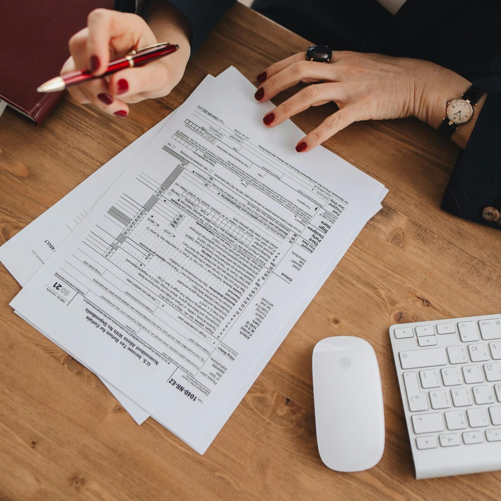 Das Bild zeigt, wie ein Mensch Dokumente ausfüült. Man sieht das Dokument von oben, die Händer der Person sind am Rand des Bildes zu sehen.